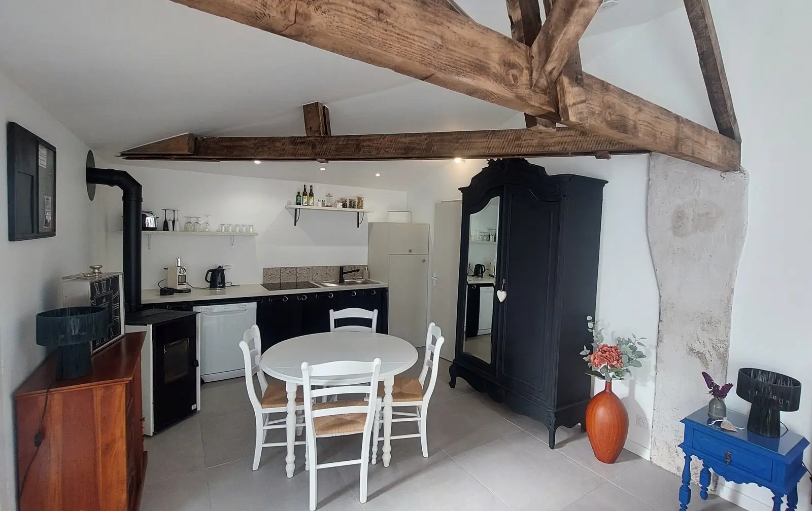 Cuisine et salle à manger rénovée avec poele, frigo, plaque de cuisson et machine à café/bouilloire. 