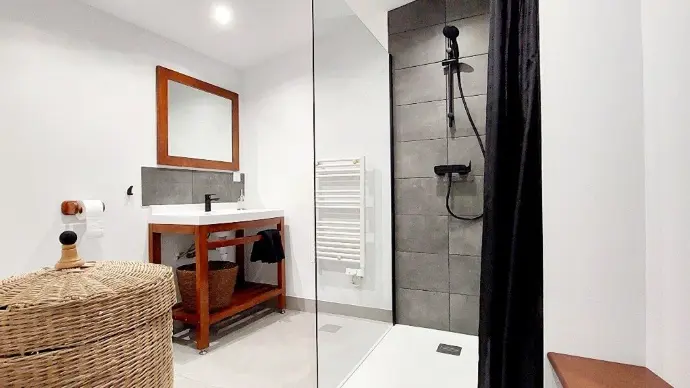 Salle de bain rénovée et moderne avec douche et lavabo.