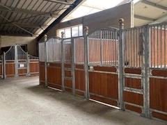 Boxes en bois spacieux avec portes fermées par une grille