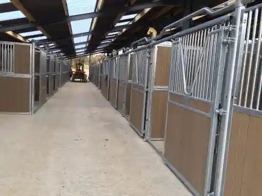 Écurie intérieure avec boxes en bois à portes coulissantes et allée centrale